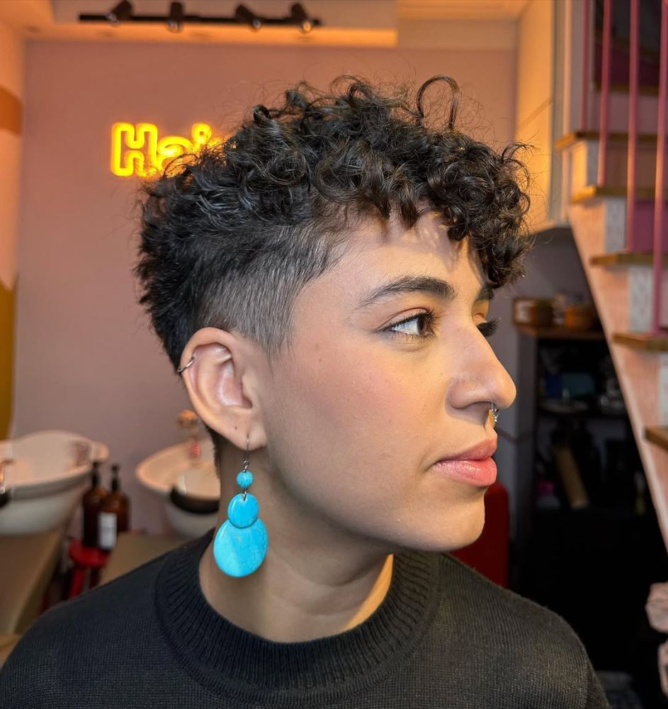 Profile view of a woman with dark ringlets on top and a clean faded undercut on the side