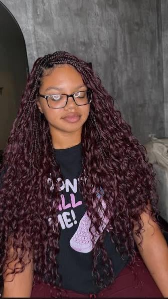 Long boho box braids with curly ends in a deep burgundy cherry cola blend