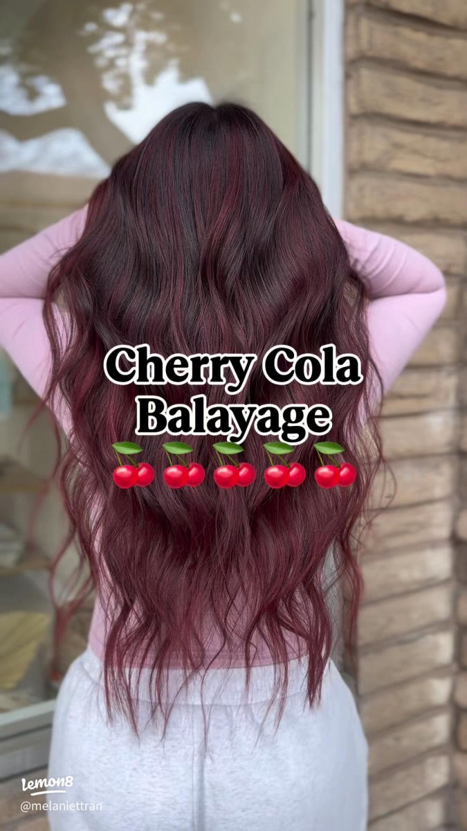 Back view of long wavy hair with a seamless dark root melting into cherry cola balayage