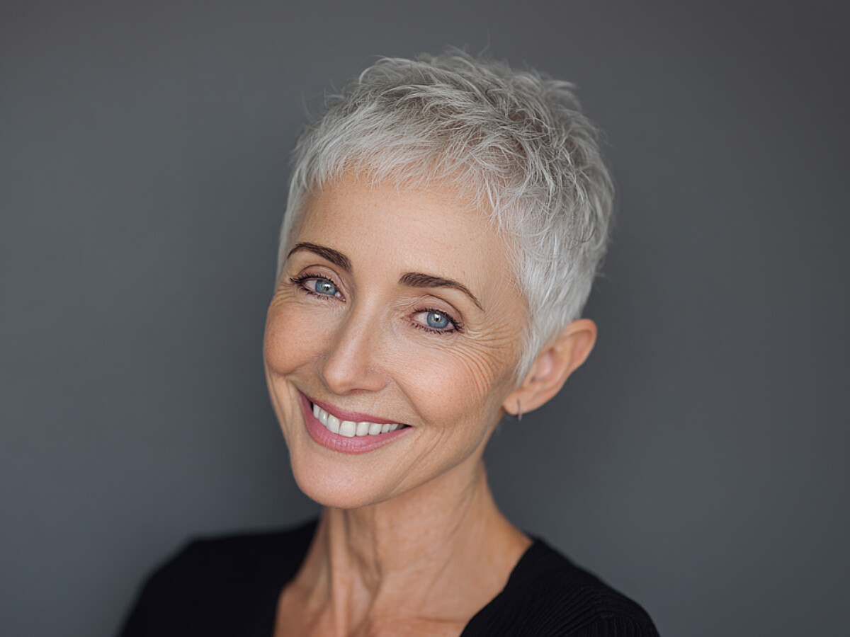 Very short cropped white hair micro pixie cut on an older woman