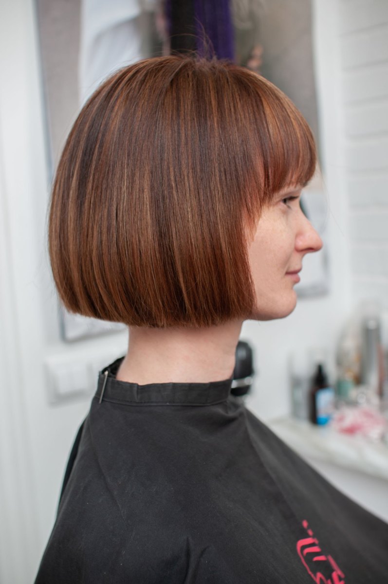 Chin-length French bob with bangs in a warm mahogany cherry shade