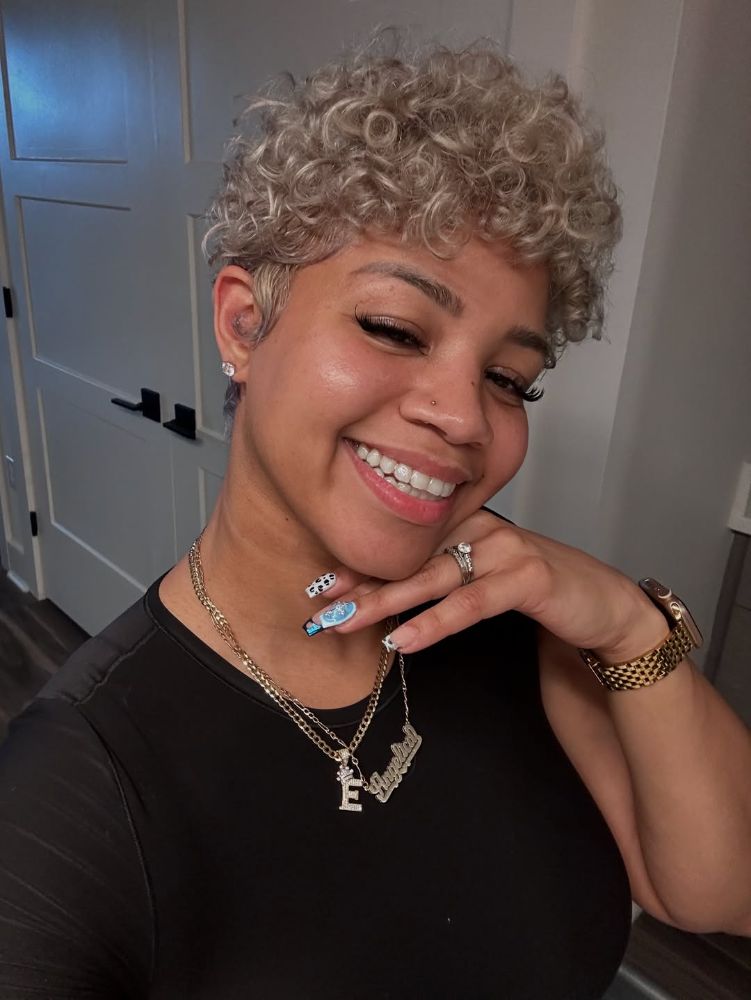 Smiling woman with an icy platinum blonde tightly curled pixie cut