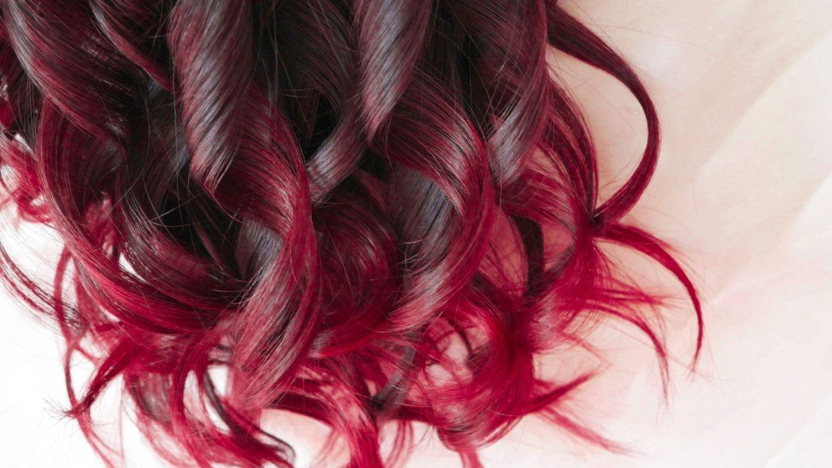 Close-up of dark brown curls melting into vibrant cherry red tips