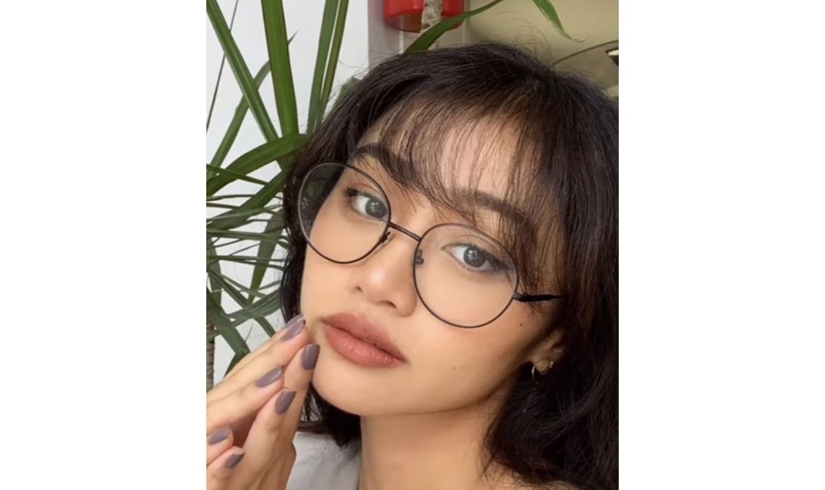 Woman wearing round wire glasses with thin Korean wispy bangs