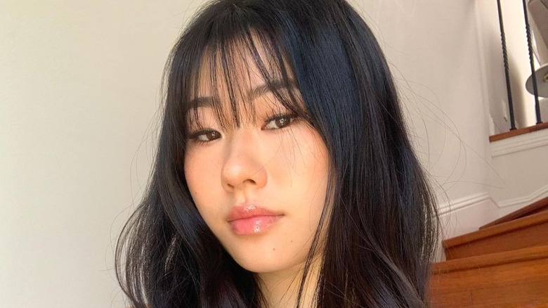 Young woman with sleek straight dark hair and light Korean air wispy bangs