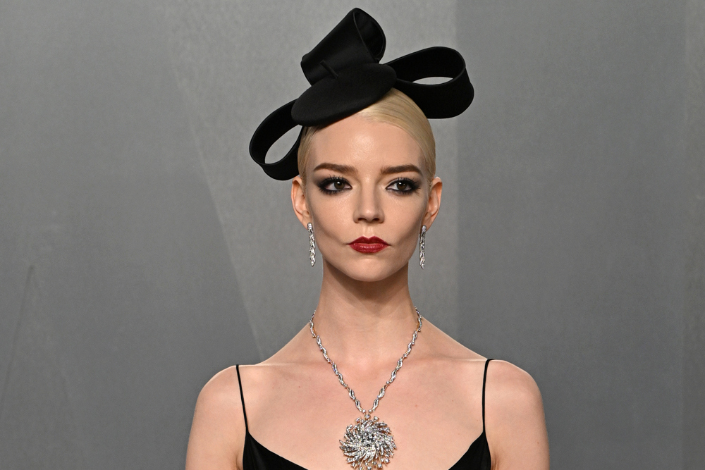 Anya Taylor-Joy wearing a sleek blonde updo with a giant black bow